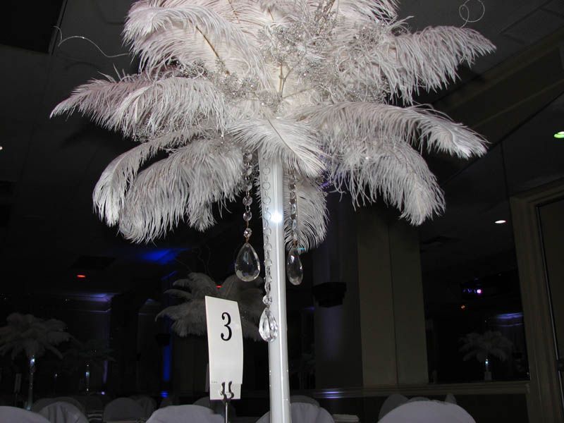 White ostrich feather centerpiece with dangling crystals on table with number 3.