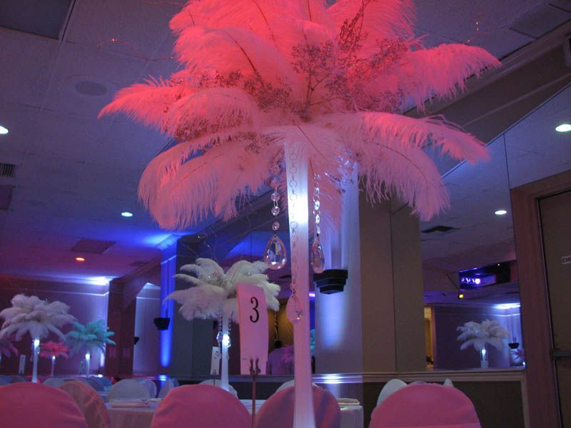 White feather centerpiece on a table, lit with pink and blue lights.
