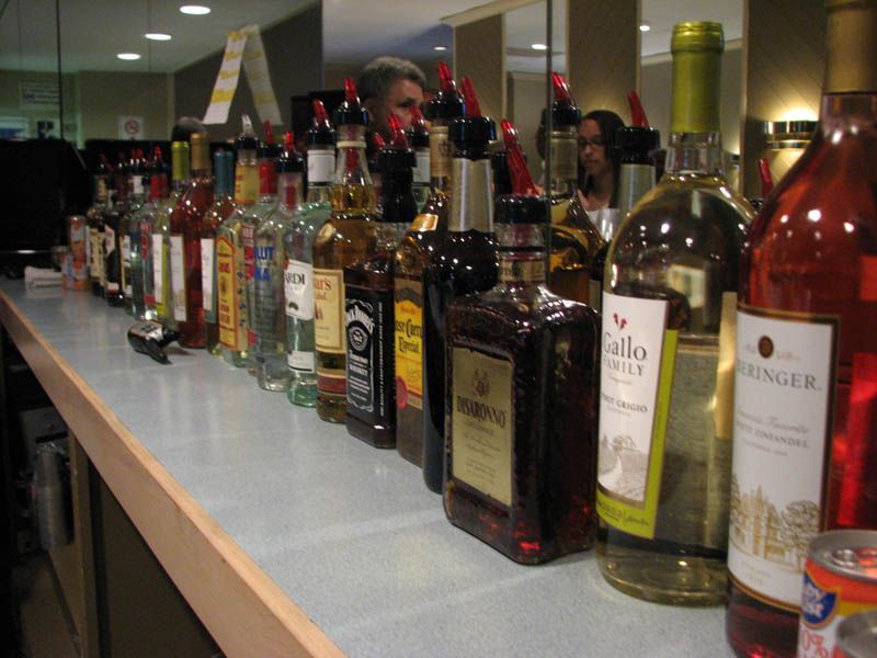 Bar lined with liquor bottles, bartender in background.