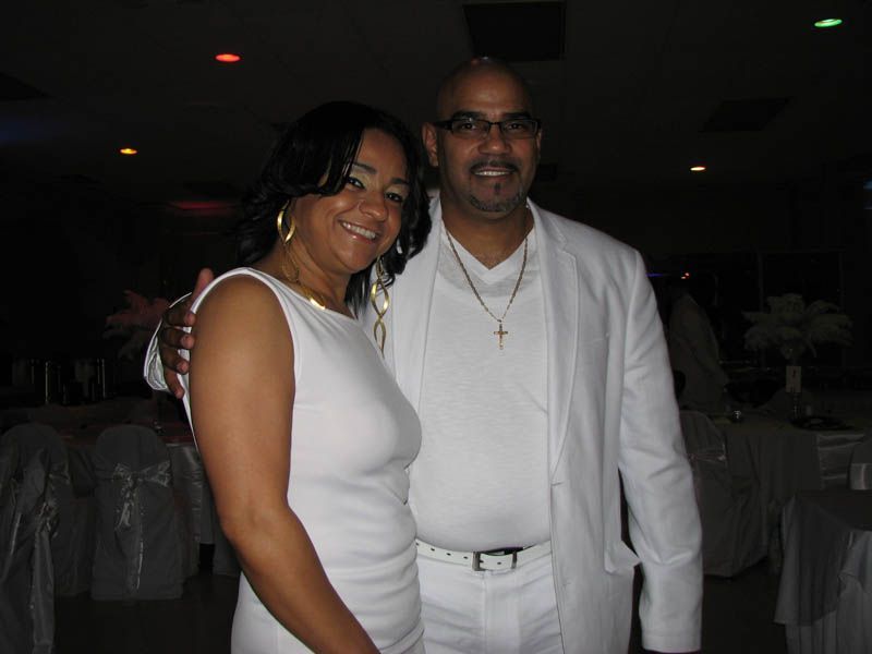 Couple in white formal attire posing together at an event.