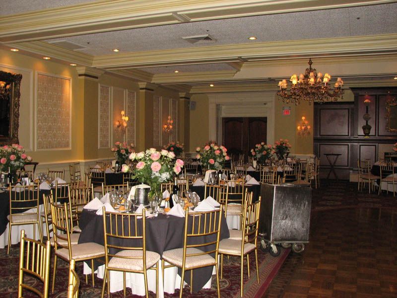 Banquet room with round tables, gold chairs, floral centerpieces, and a chandelier.
