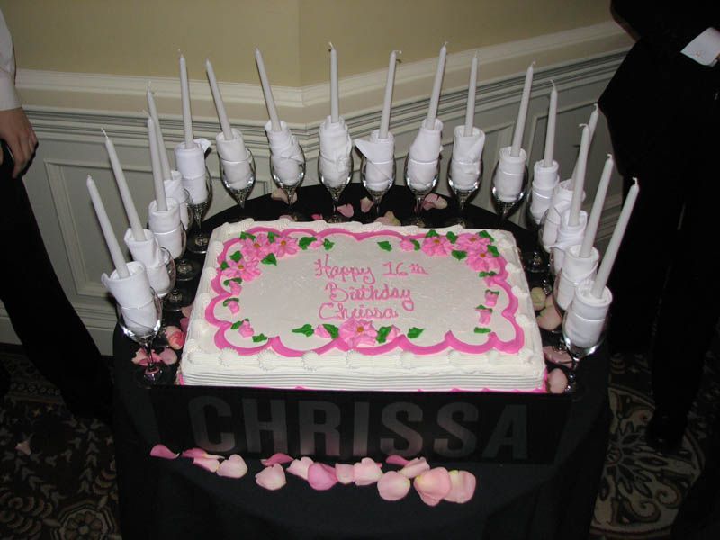 Birthday cake with pink frosting, surrounded by candles in holders, reads 