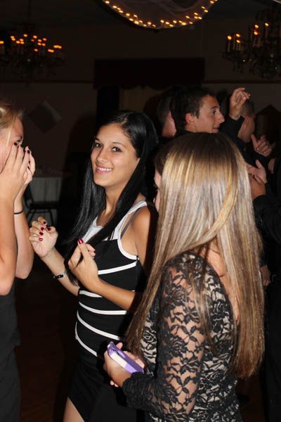 People dancing at a party; woman in striped top smiles, others in background.