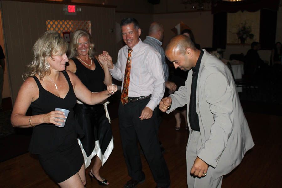 People dancing at a party: four people dancing in a dimly lit room, some holding hands, others making fists.