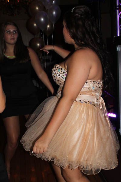 Woman in a formal dress dancing at a party with balloons in the background.