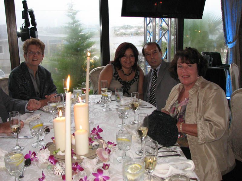People seated at a festively decorated table with candles, champagne glasses, and flowers, by a window.