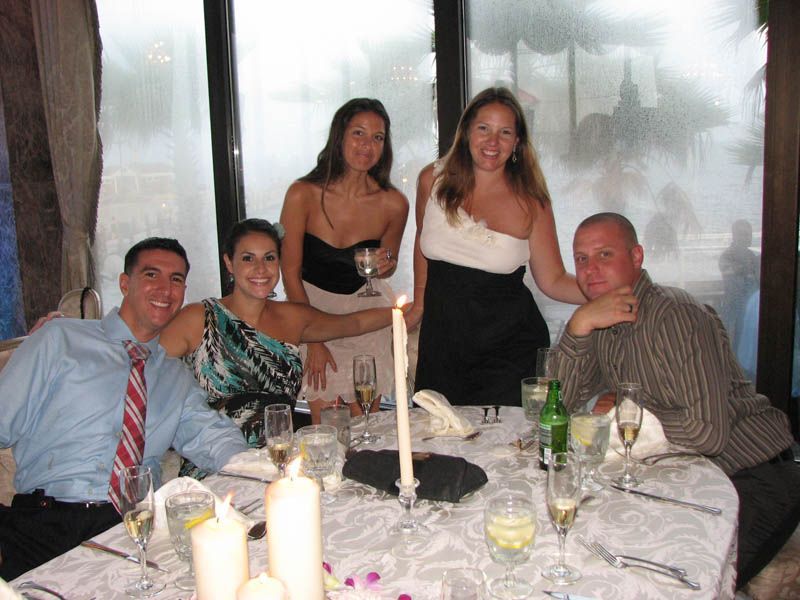Group of people at a candlelit table, celebrating. A woman holds a lit candle, smiling.
