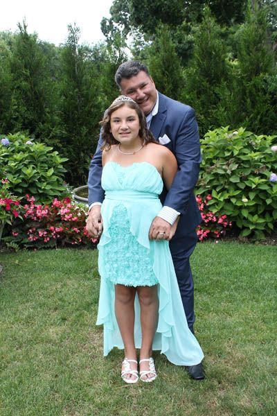Man in blue suit embraces girl in turquoise dress in a garden.