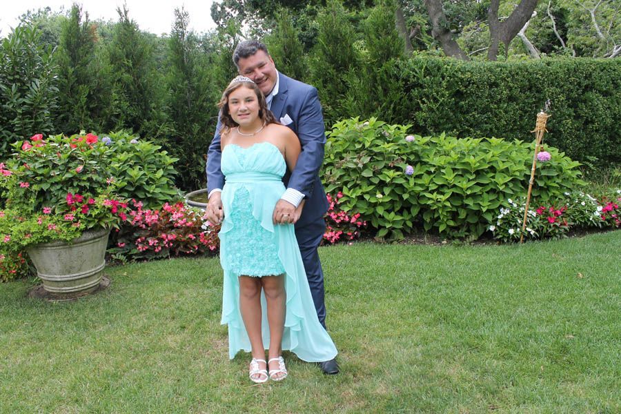 Man in blue suit embraces girl in turquoise dress in a garden.