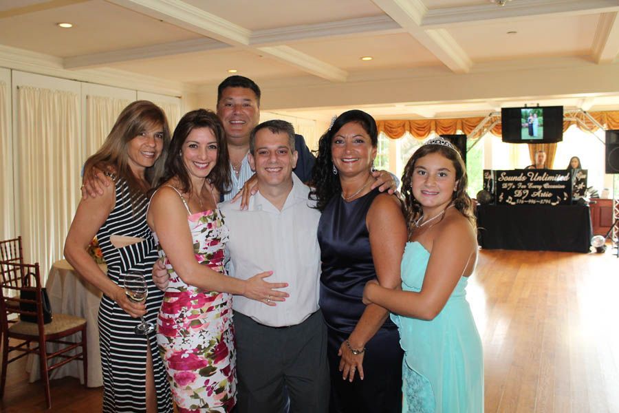 Group of seven people smiling, posing together indoors at an event.