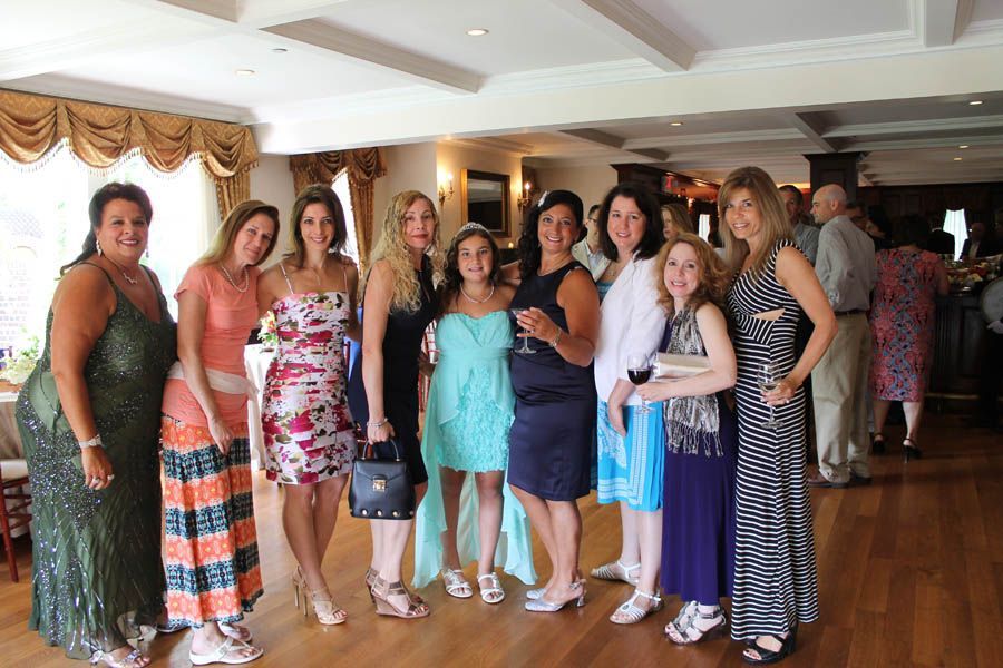 Group of people posing for a photo indoors, in a bright room with wood floors.