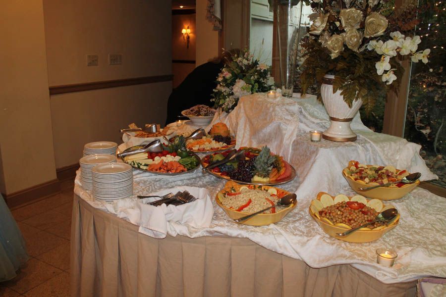 Buffet table laden with food: fruit, vegetables, dips, and prepared dishes, elegantly arranged.