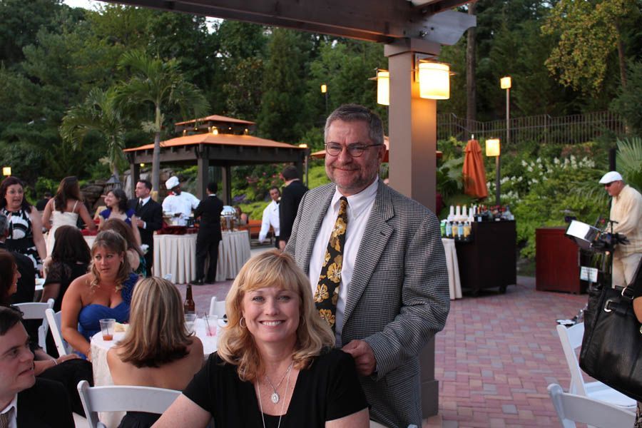 Couple at outdoor event with gazebo and people.