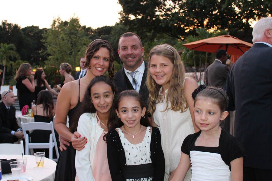 Family of six smiling together at an outdoor event, some in formal wear.