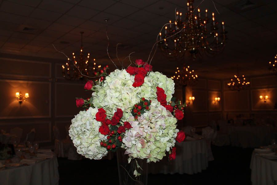 Centerpiece: white hydrangeas, red roses, brown branches in a vase; formal dining room setting.