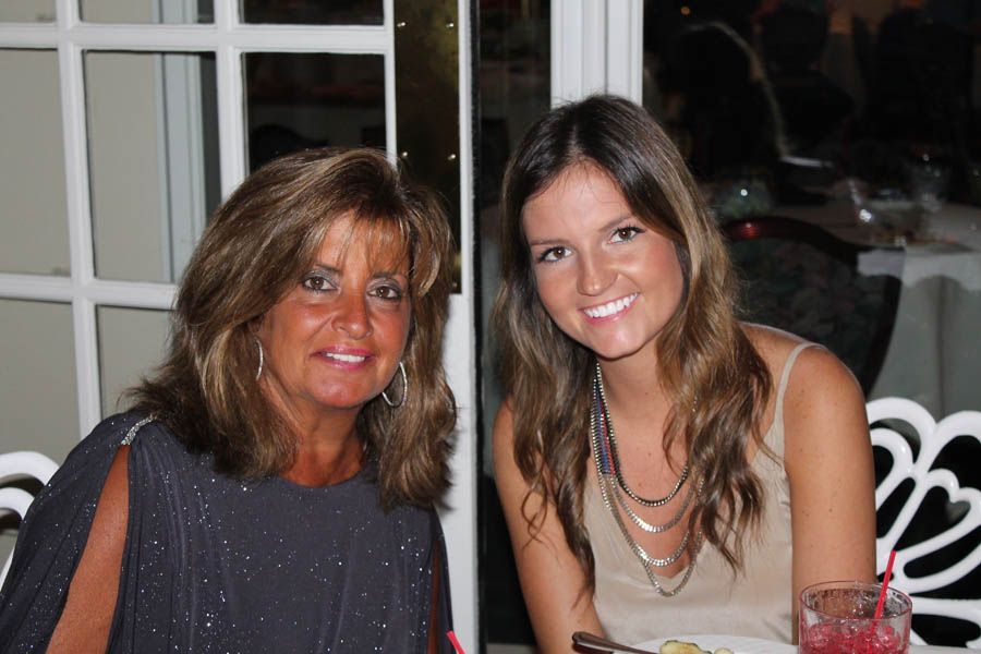 Two women smiling indoors, possibly a restaurant. One with dark hair, the other with light.