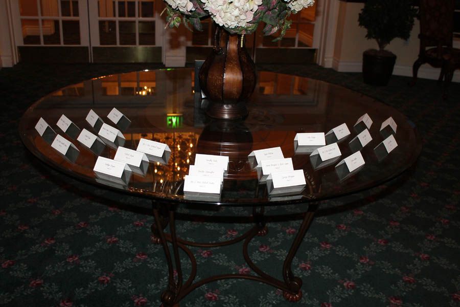 Glass table with name cards around a flower arrangement.