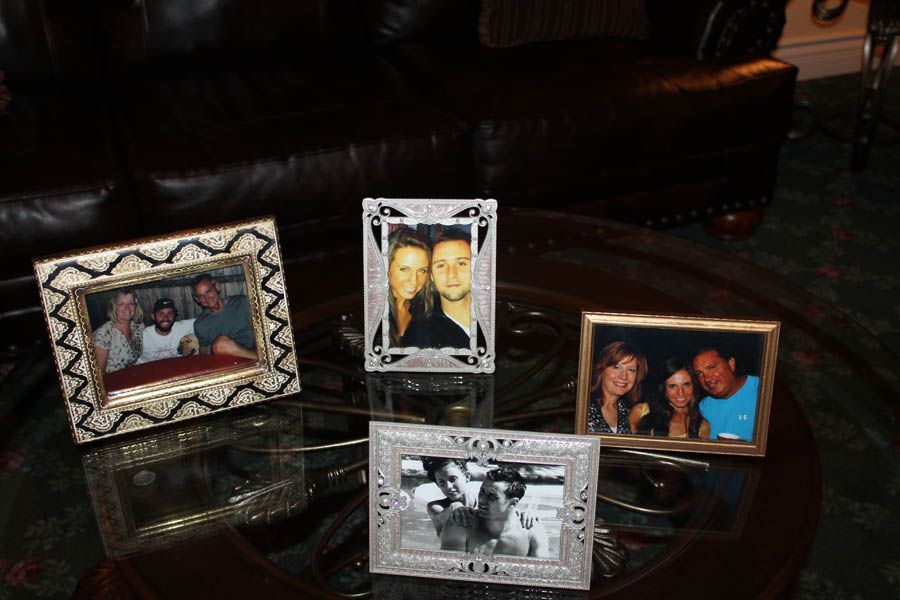 Four framed photos on a glass table in front of a leather sofa.
