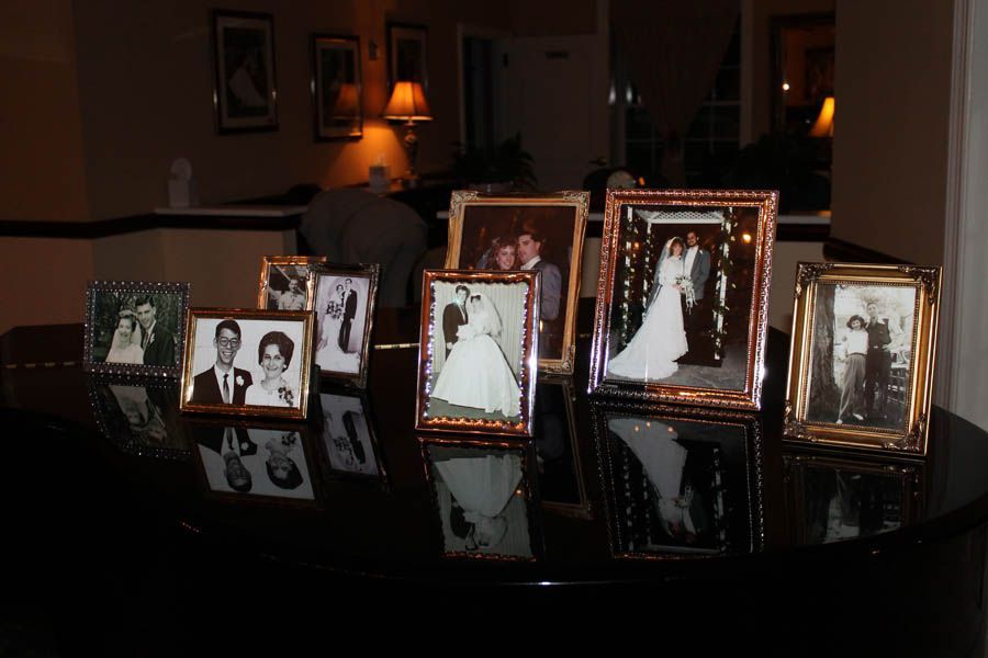 Framed wedding photos displayed on a dark surface, under warm lighting.