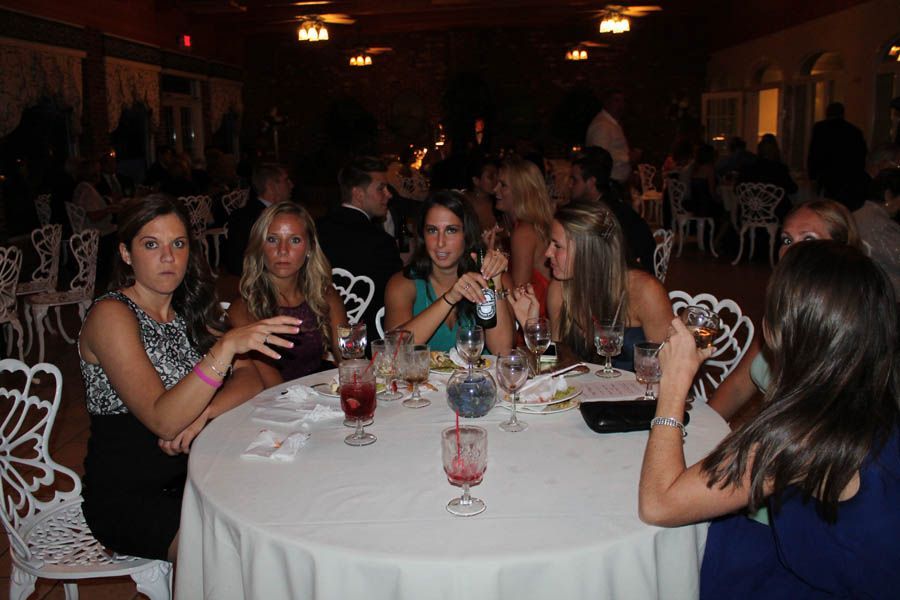 A group of people sitting at a round table at an event, with drinks and food.