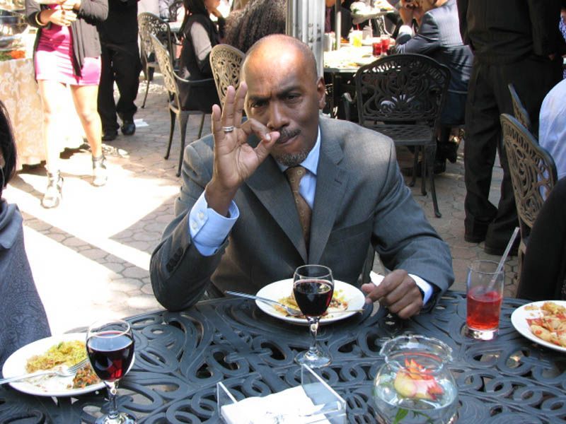 Man in a suit at outdoor cafe, making 