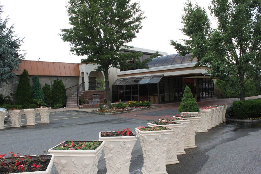 Building entrance with flower planters and trees in front.