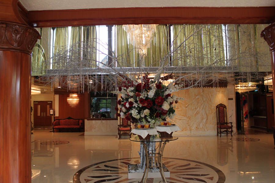 Elegant hotel lobby with floral arrangement, chandelier, columns, and patterned floor.