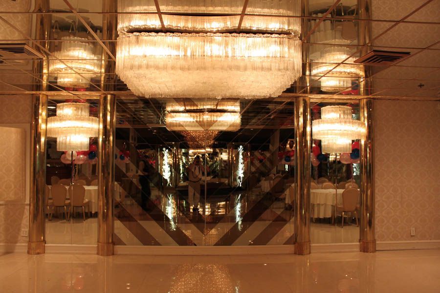 Ballroom entrance with gold-framed mirrored walls reflecting chandeliers and tables.
