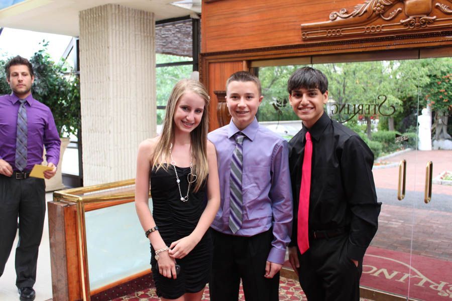 Group of people dressed up, standing near a door. A man in purple stands in the background.
