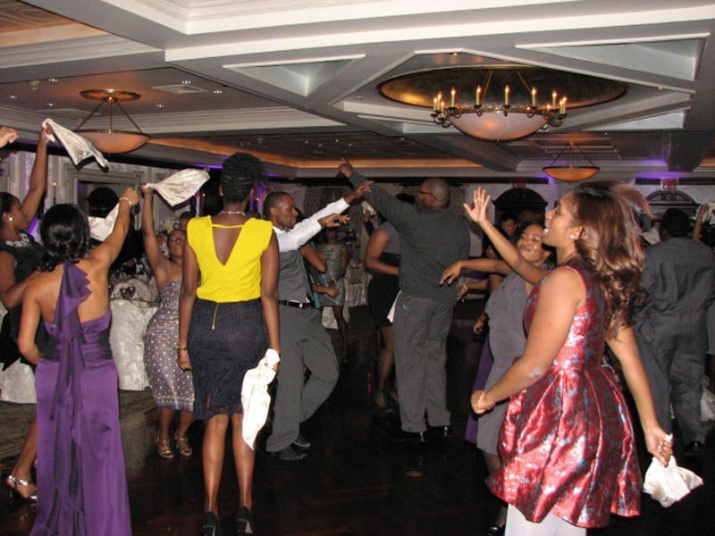 People dancing joyfully at an indoor event, some waving items.