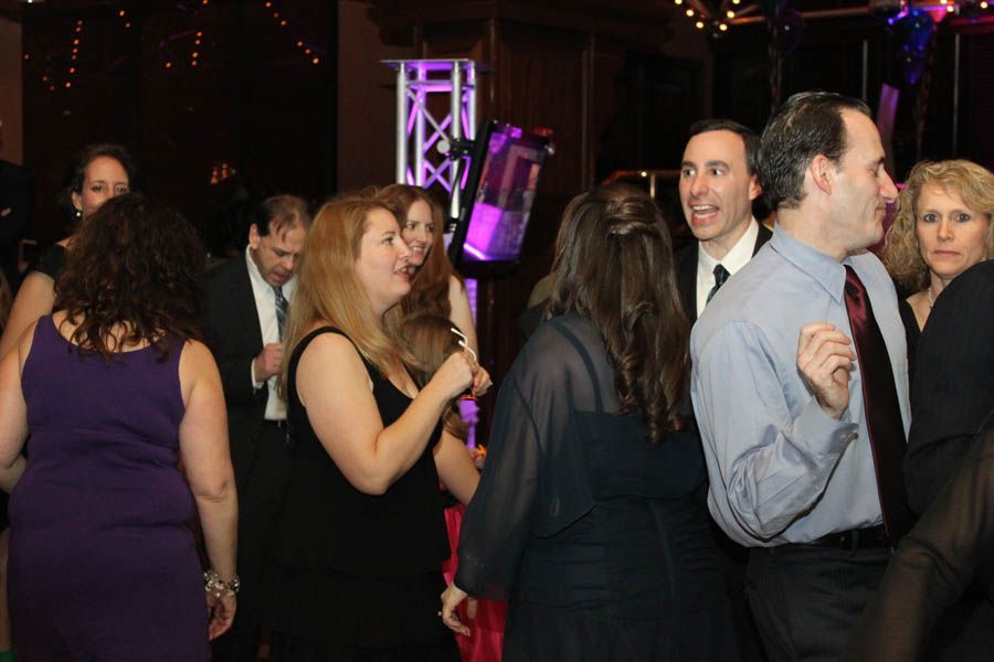 People dancing at a party, illuminated by stage lights.