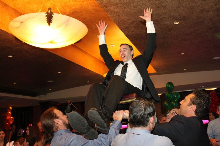 Man lifted up in the air by a group, celebrating at a party.