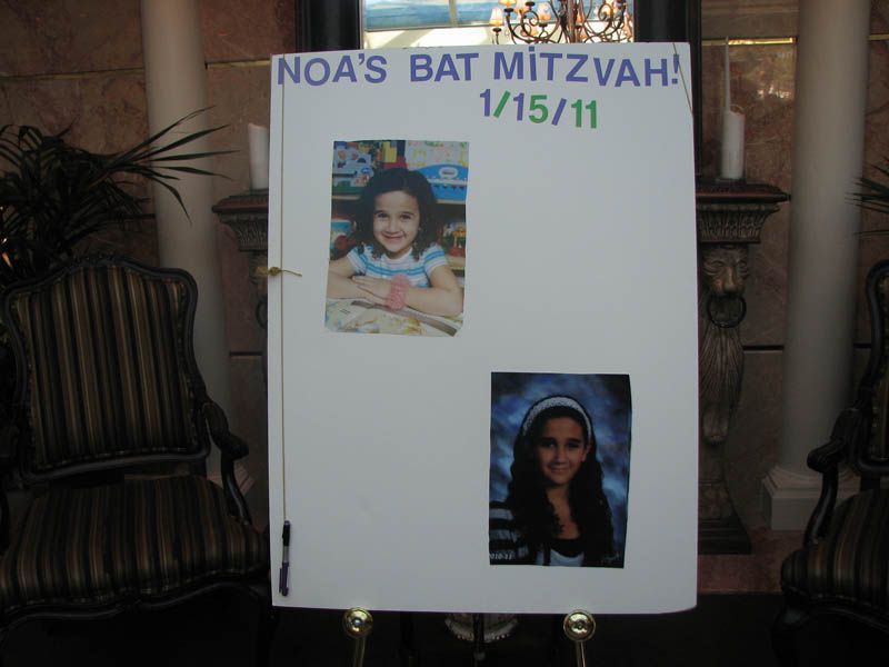 Sign for Noa's Bat Mitzvah, 1/15/11, with two photos of Noa. Standing on a gold easel.
