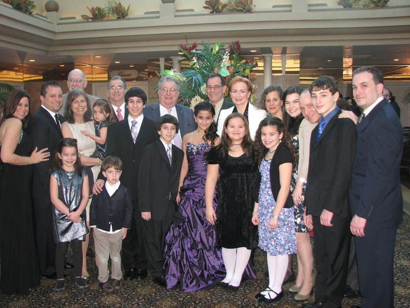 Group of people, formal attire, posing in an ornate setting. Smiles, various outfits.