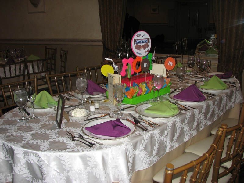 Festive table set for a 70th birthday celebration with purple and green napkins, centerpiece, and place settings.