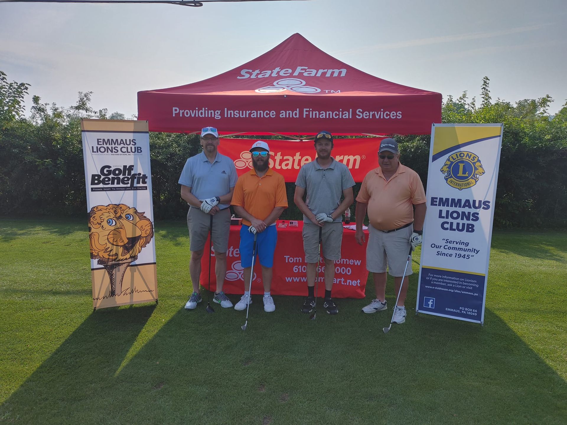 A group of men standing in front of a tent that says state farm