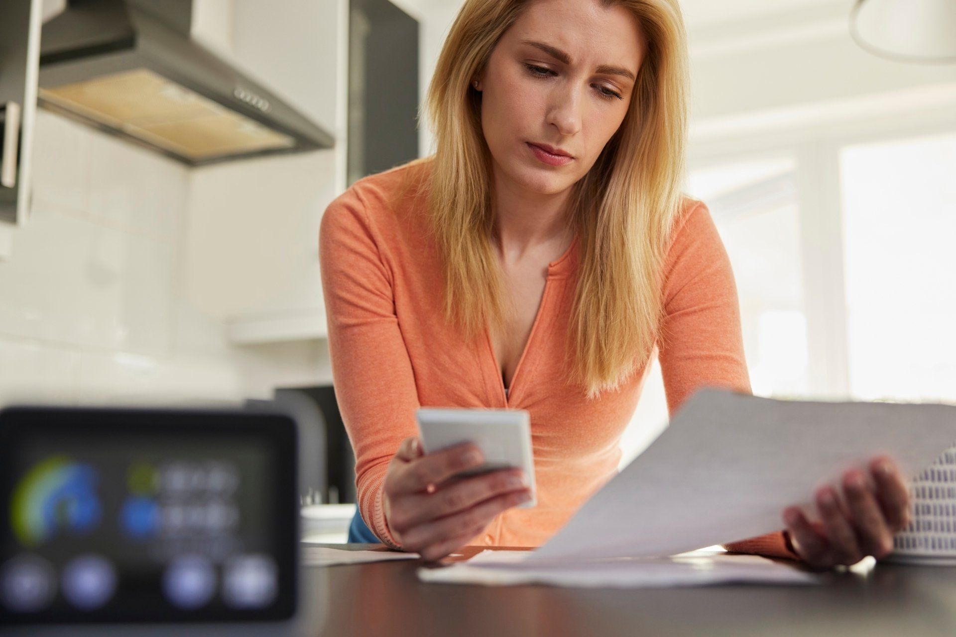 A woman is sitting at a table looking at papers and a cell phone. A woman is sitting at a table looking at papers and a cell phone.