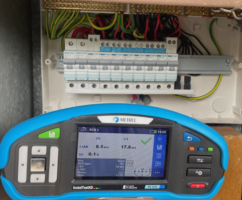 Man in yellow workwear tests electrical panel with a multimeter.