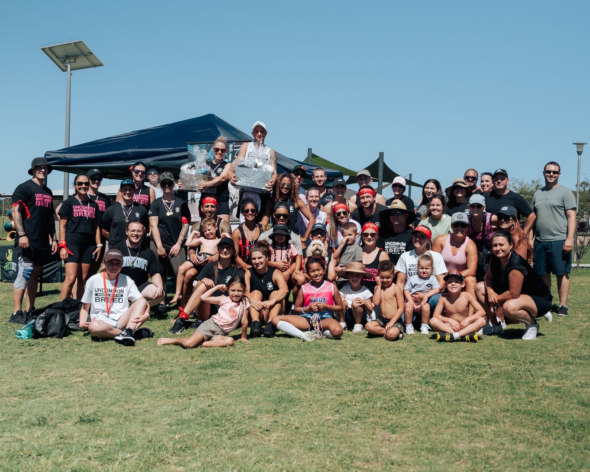 Group of people posing for a photo on a grassy field on a sunny day.