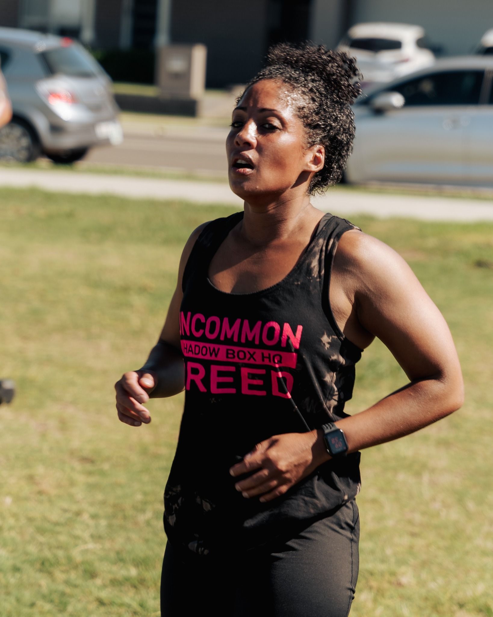 Woman in black tank top running on grass. 