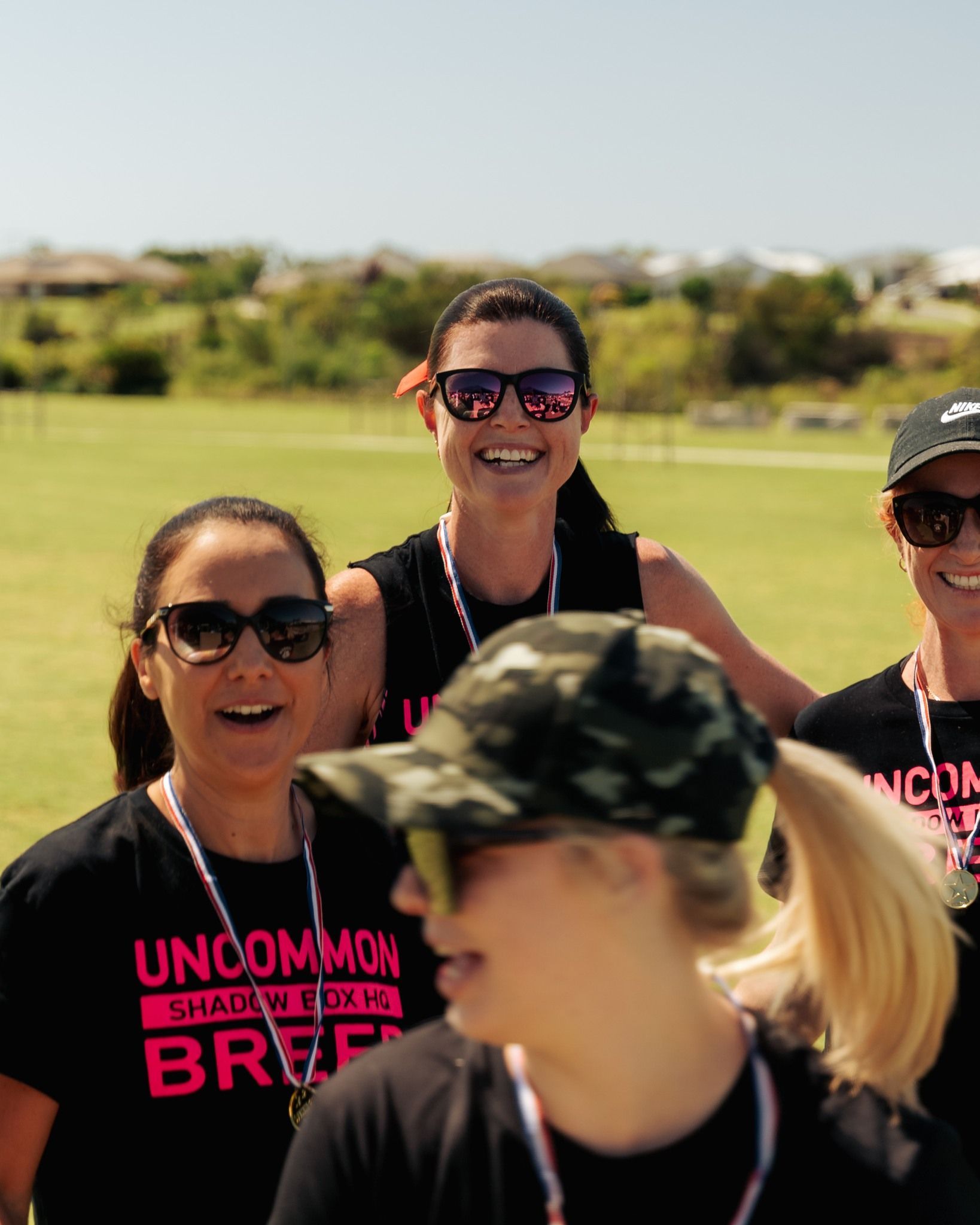 Group of people wearing sunglasses, smiling, and wearing 