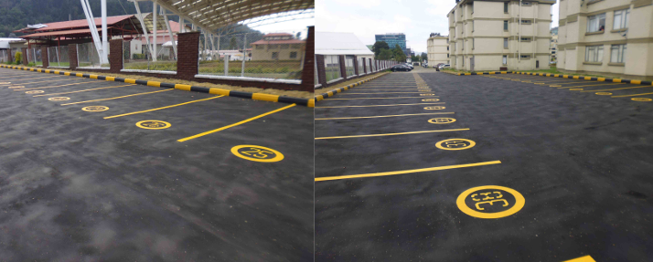 Persona que pinta una pared de ladrillos desde una escalera, vistiendo casco y ropa de trabajo oscura.