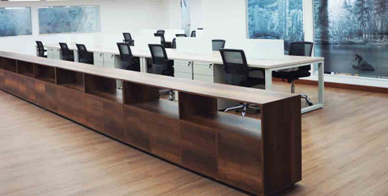 Persona que pinta una pared de ladrillos desde una escalera, vistiendo casco y ropa de trabajo oscura.