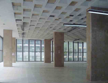 Obrero de la construcción con arnés aplicando estuco a la pared de ladrillo de un edificio.