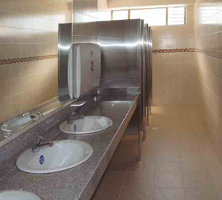 Limpiador de ventanas con equipo de seguridad pintando una moldura azul en un edificio de ladrillo.