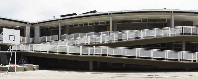 Obrero de la construcción con arnés aplicando estuco a la pared de ladrillo de un edificio.