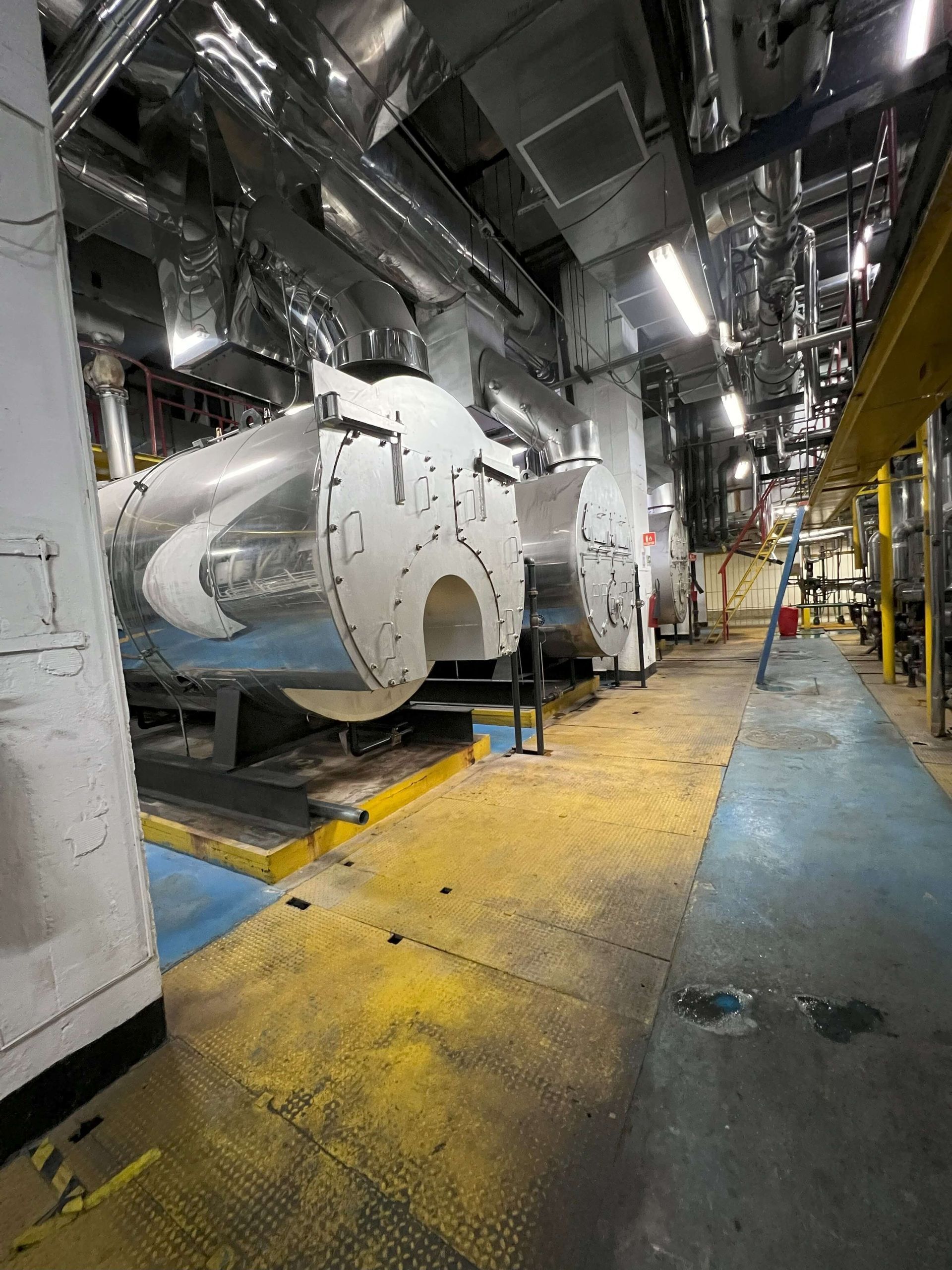 Equipo industrial de gran tamaño en un entorno interior metálico con suelo de color amarillo y azul.