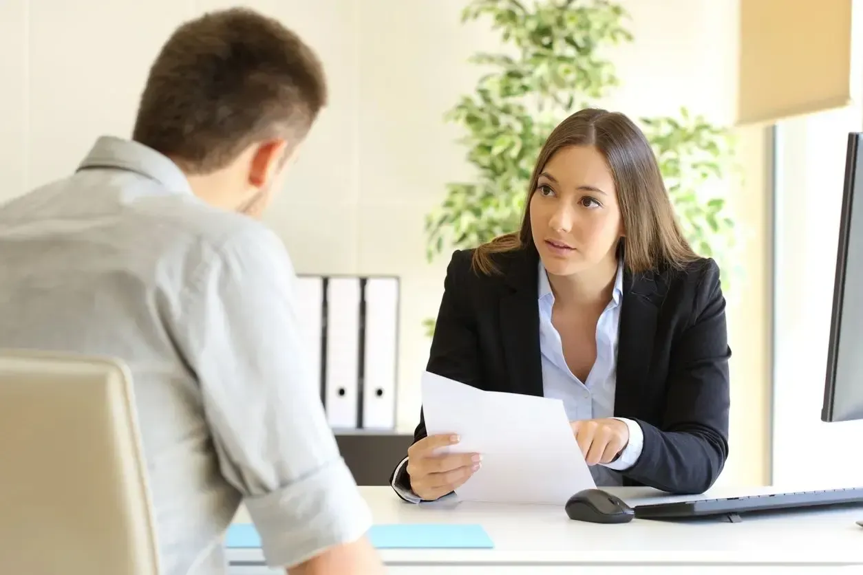 A woman is holding a piece of paper while talking to a man.