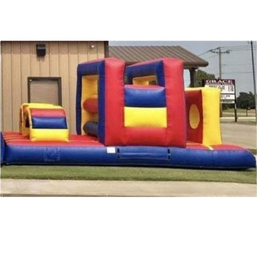 Blue inflatable triple slide with palm-tree decorations on a grassy field under a clear sky