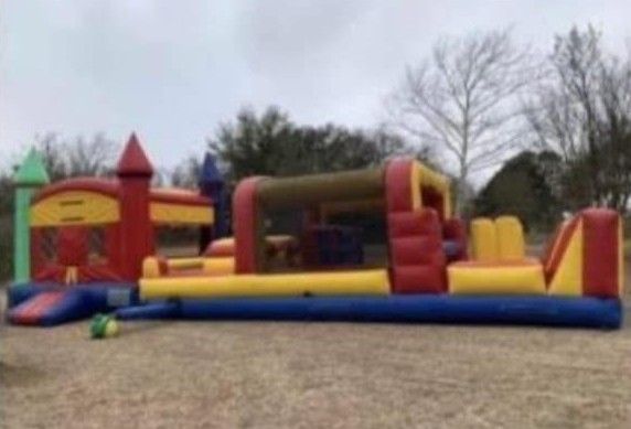 Colorful inflatable bounce slide on a grassy yard beside a brick house under a cloudy sky